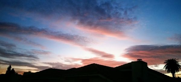 Low angle view of silhouette houses against sky during sunset