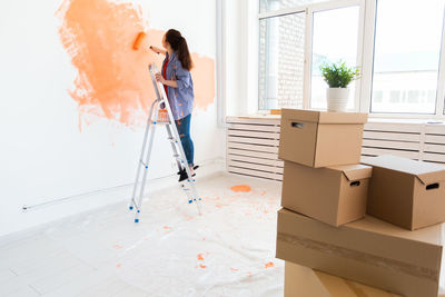 Young woman painting wall at home