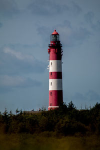 Low angle view of lighthouse by building against sky