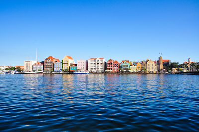 Sea by buildings against clear blue sky