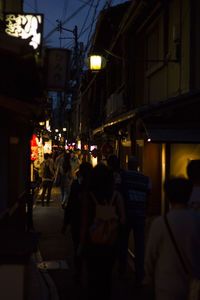 People walking on illuminated street in city at night