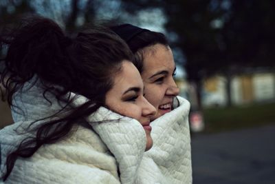 Close-up of happy female friends wrapped in blanket