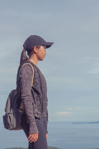 Side view of young woman looking at sea against sky