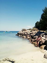 Woman sitting on beach against clear sky