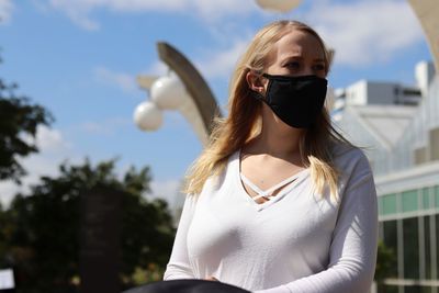 Portrait of young woman against sky wearing a mask