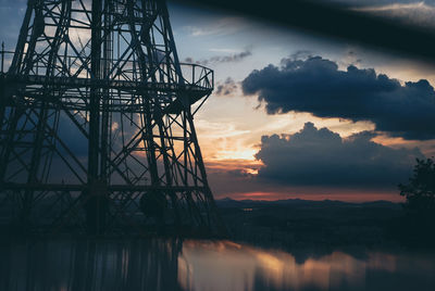 Low angle view of silhouette electricity pylon against sky during sunset