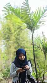 Young woman using mobile phone while sitting in park