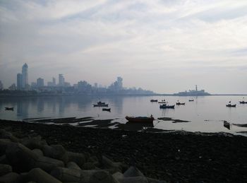 Scenic view of river by city against sky