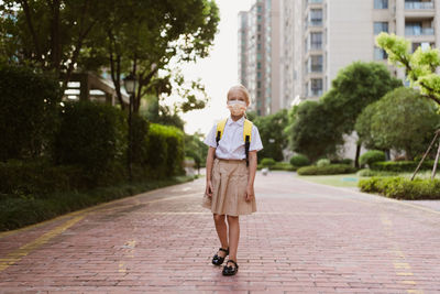 Full length of girl walking on footpath in city