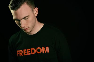 Close-up of man wearing t-shirt with freedom text against black background