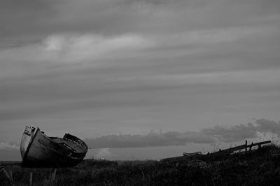 Abandoned ship on field against sky