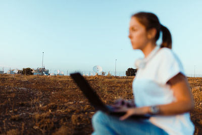 Side view of man using mobile phone on field