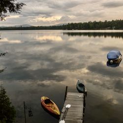 Boats moored in lake against sky during sunset