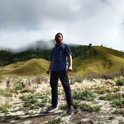 Young man standing on land against sky