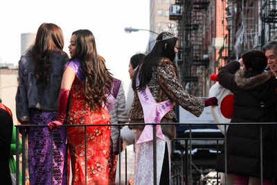 Rear view of people standing by railing in city