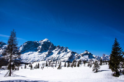 Scenic view of snow covered mountains against blue sky