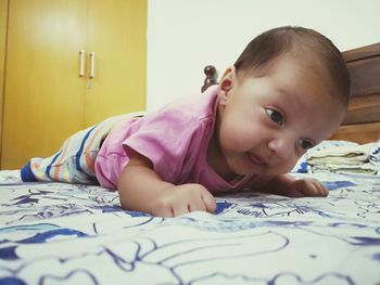 Portrait of cute boy lying on bed at home