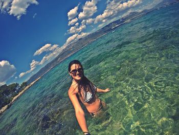 Portrait of young woman wearing bikini standing in sea