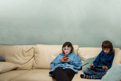 Side view of woman sitting on sofa at home