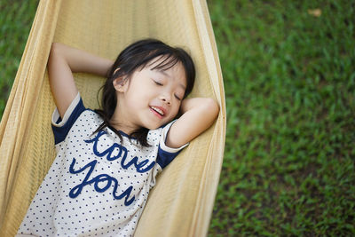 High angle view of smiling girl with closed eyes in hammock over field