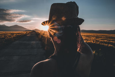 Portrait of young woman in hat against sky during sunset