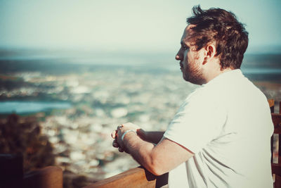 Side view of young man looking at sea