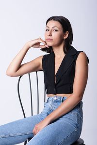 Beautiful young girl sitting on a chair and posing in a studio w