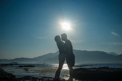 Side view of silhouette couple standing against sky