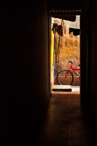 Bicycle parked by wall seen through open door