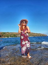 Woman standing at beach against clear blue sky