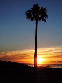 Silhouette palm trees on beach against sky at sunset