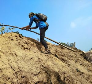 Low angle view of man on rock against sky