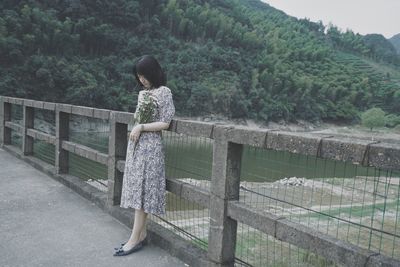 Woman standing on railing against mountain