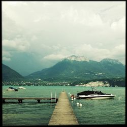 Boats in sea against cloudy sky