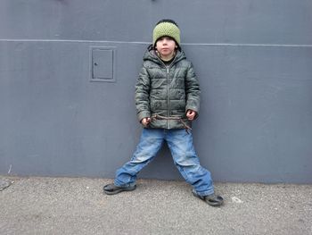 Full length portrait of boy standing against wall