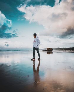 Full length of man standing on beach against sky