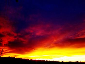 Silhouette landscape against dramatic sky during sunset