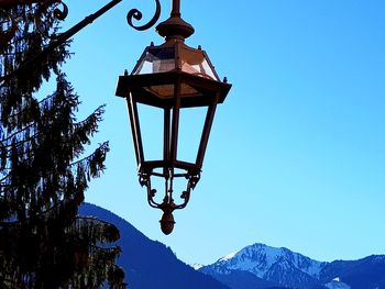 Low angle view of windmill and mountains against clear blue sky