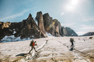 Mounatineers cross a glacial crevasses on a sunny day, baffin island.