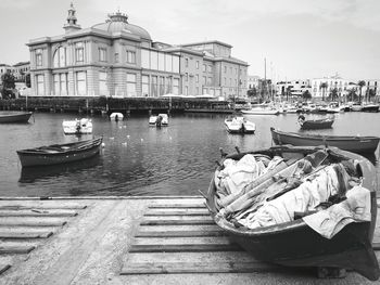 Boats moored at harbor against sky in city