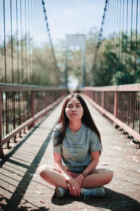 Young woman sitting on footbridge
