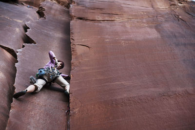 Low angle view of hiker climbing cliff