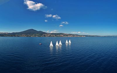 Sailboats in sea against blue sky