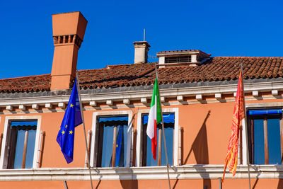 Low angle view of clothes drying on building against clear blue sky