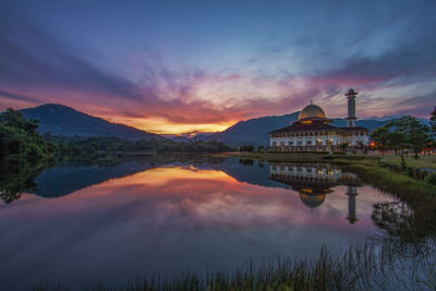 Scenic view of lake against cloudy sky during sunset