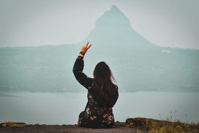 Rear view of woman in lake against sky