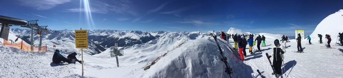 Panoramic view of people on snowcapped mountains against sky