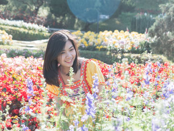 Young woman smiling while standing by flowering plants