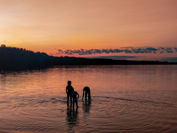 Silhouette men standing against orange sky during sunset