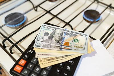 Banknotes lie next to a burning gas burner along with a calculator.